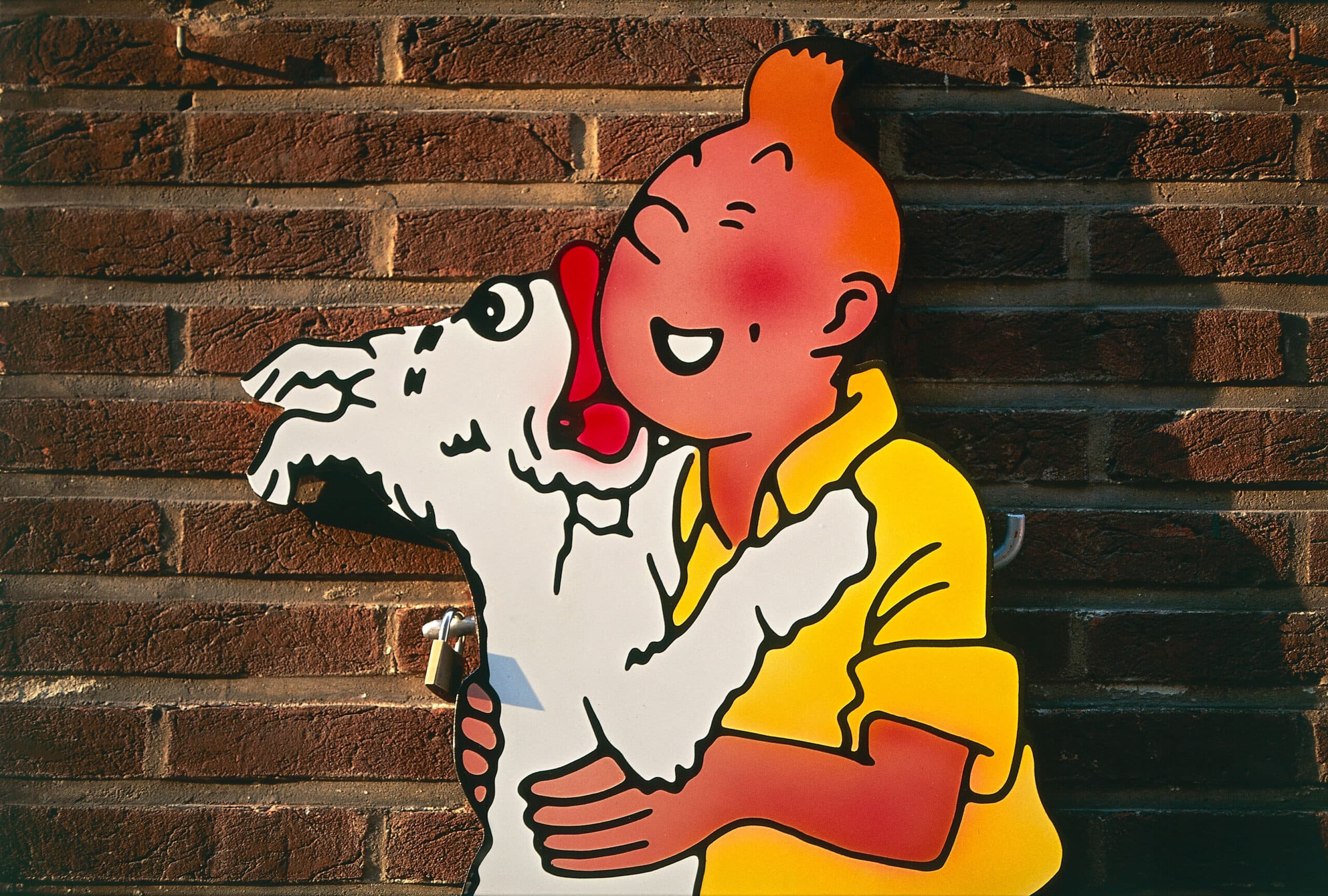 The comic figures of Tintin on a plaque in front of a brick wall